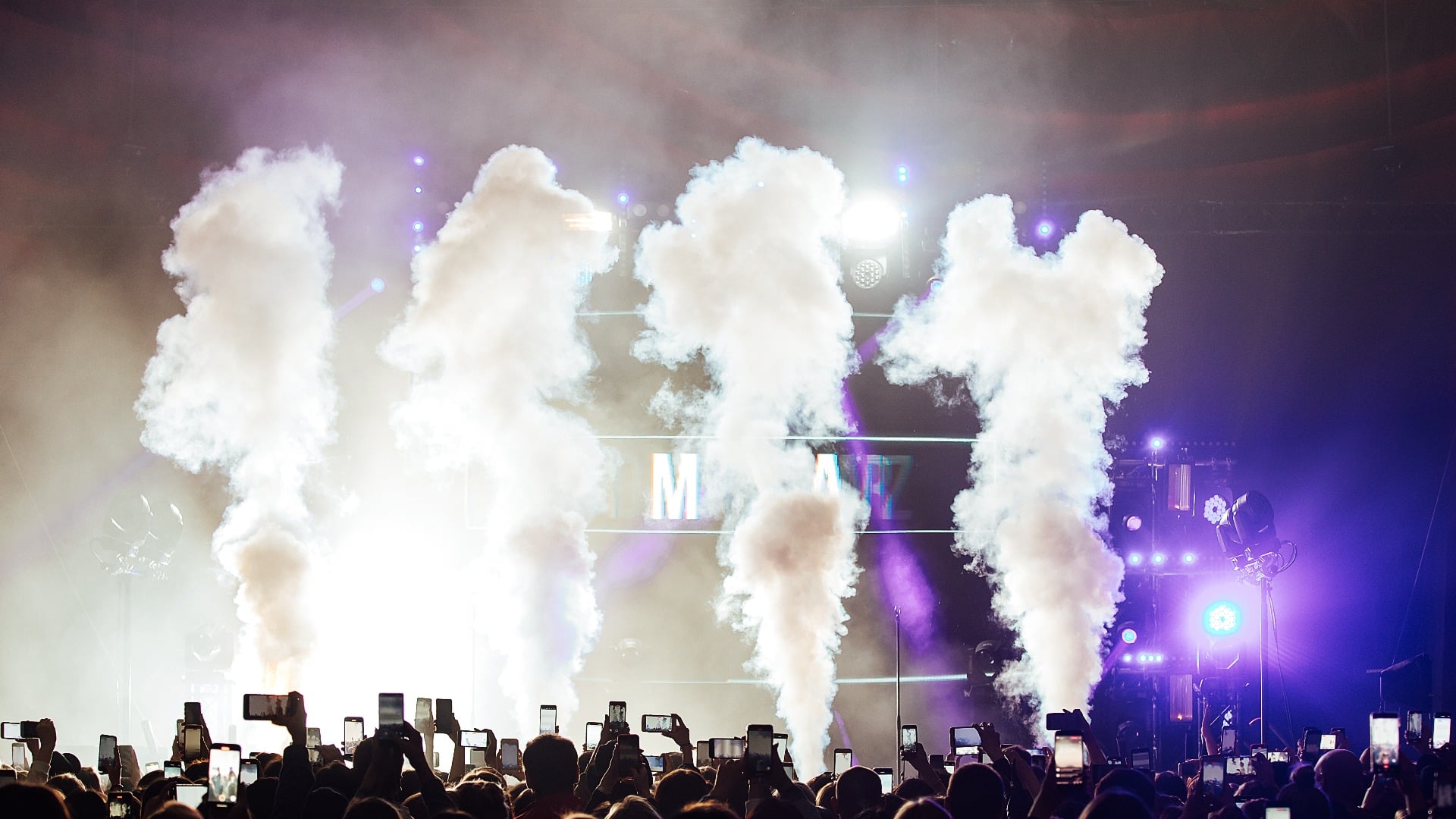 a smoke machine at a concert. smoke cannons generate columns of smoke. special effects at a music concert for a crowd of spectators. dancing in the hall