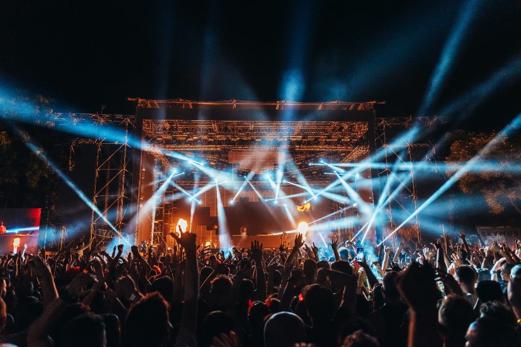 Silhouettes of concert crowd in front of bright stage lights on a music festival