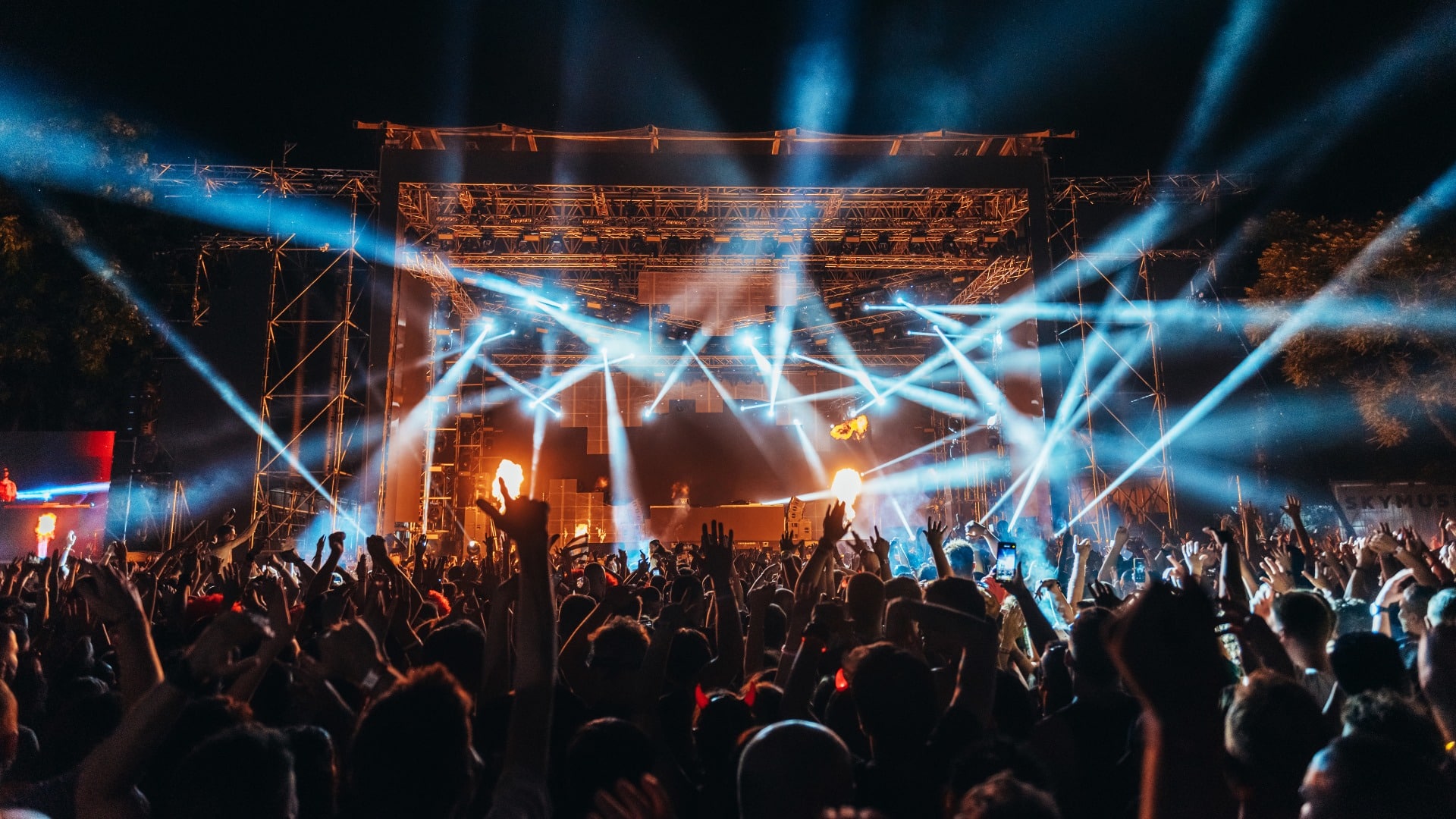 Silhouettes of concert crowd in front of bright stage lights on a music festival